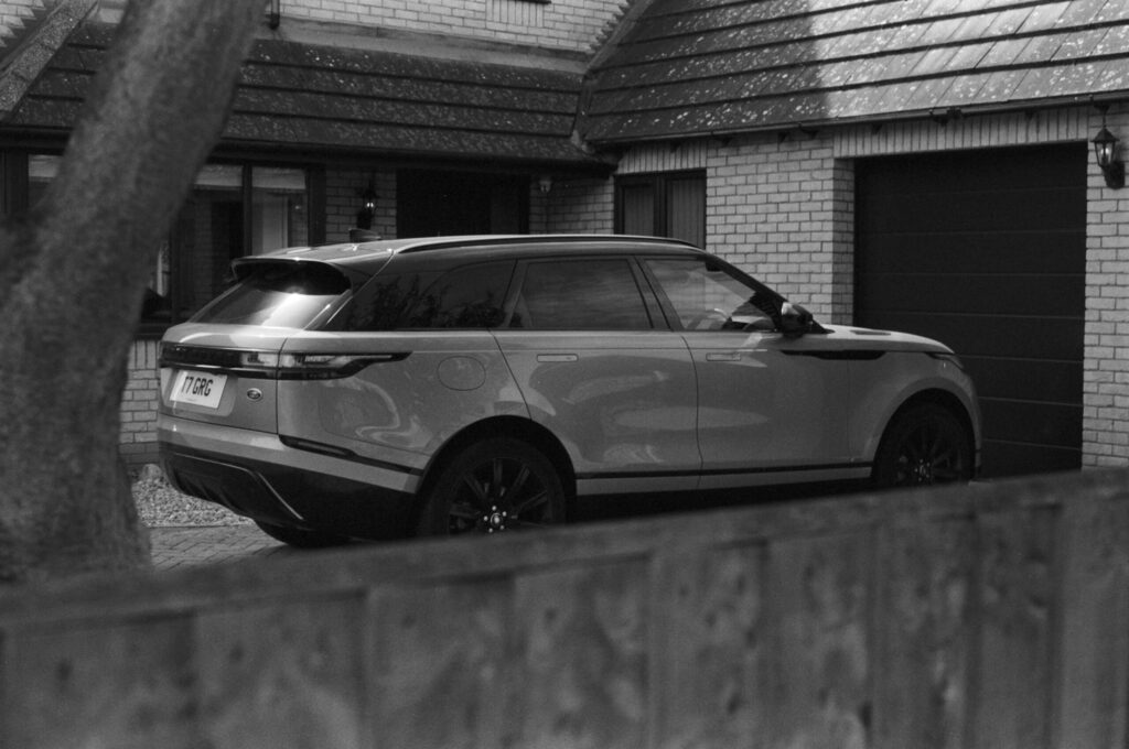 A dark SUV parked on a driveway to cut driving costs.